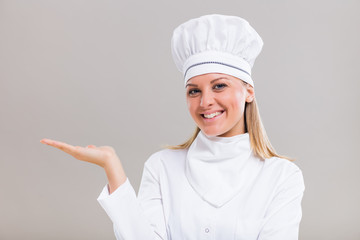 Portrait of beautiful female chef gesturing on gray background.
