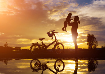 Obraz premium Reflection Silhouette of mother with her toddler against the sun