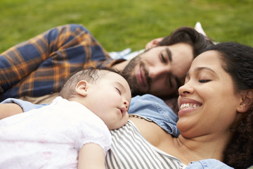 Fototapeta premium Family With Baby Relaxing On Rug In Garden Together