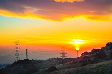 Sun appears to be setting on an electrical power tower.