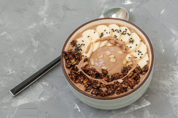 Breakfast smoothie bowl topped with chocolate muesli and banana. Love for a healthy vegan food concept