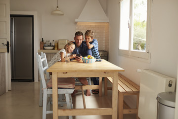 Children Looking At Mobile Phone With Father