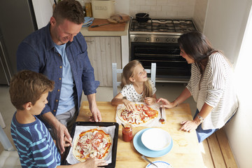 Family At Home In Kitchen Making Pizzas Together