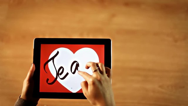 Te amo calligraphy. Female writing inside white heart on tablet hd