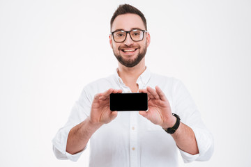 Smiling young bearded man showing phone display to camera