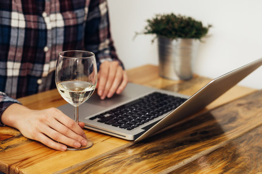 Closeup of woman hands with glass of wine and computer