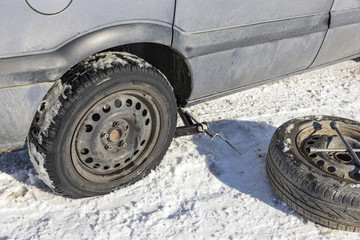 changing a flat tire in the winter snow with backup