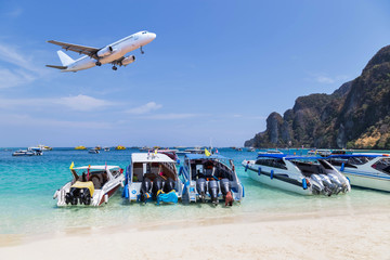 speedboats moored in the tropical sea with airplane landing above on blue sky