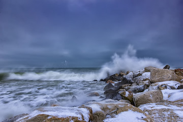 sea winter wave hits the breakwater. Stormy clouds