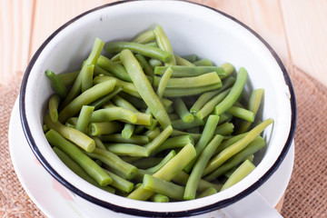 Colander with leguminous of green raw beans on the cutting board on the kitchen table