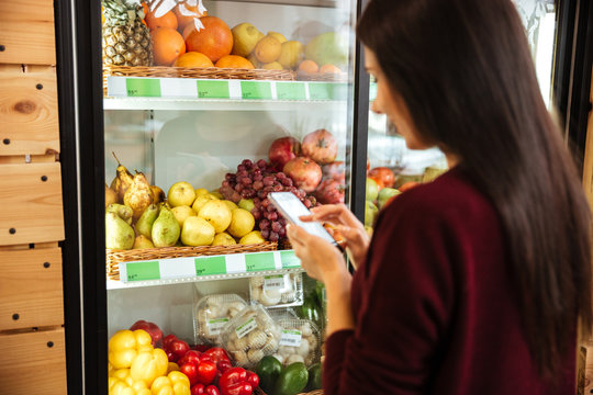 Back View Of Womanusing Cell Phone In Grocery Shop