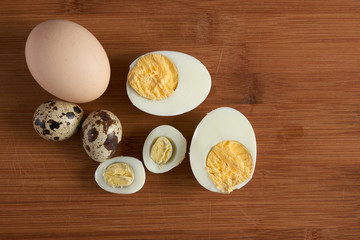 Halves of a boiled chicken and quail eggs on wooden background