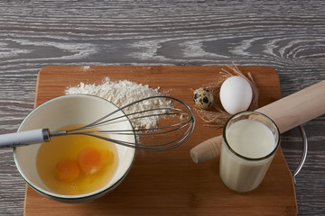 Baking ingredients for cooking. Eggs, flour, milk  over rustic wooden background.