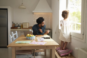 Father And Daughter Paint And Eat Pizza At Kitchen Table
