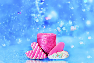 two cookies in the shape of a heart and a candle in the middle. light blue bright sparkling, festive, background.

