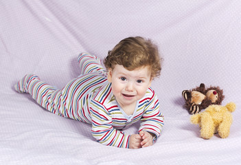 The little boy in the crib with toys. The child in the home
