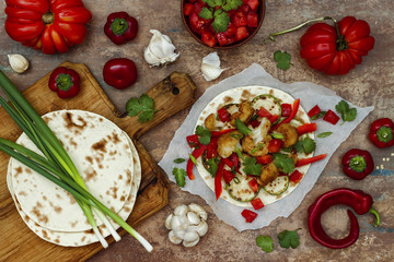 Spicy veggies tacos with roasted cauliflower,  zucchini and tomato salsa on rustic wooden cutting board. Preparing healthy lunch vegetarian snack. Top view, overhead, flat lay