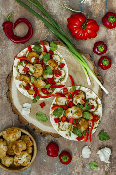 Spicy veggies tacos with roasted cauliflower,  zucchini and tomato salsa on rustic wooden cutting board. Preparing healthy lunch vegetarian snack. Top view, overhead, flat lay