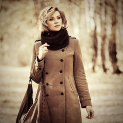 Happy blond fashion woman with handbag walking outdoor