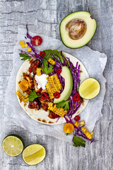 Mexican tacos with avocado, slow cooked meat, grilled corn, red cabbage slaw and chili salsa on rustic stone table. Recipe for Cinco de Mayo party. Top view. Copy space background