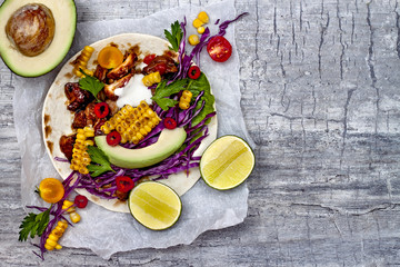 Mexican tacos with avocado, slow cooked meat, grilled corn, red cabbage slaw and chili salsa on rustic stone table. Recipe for Cinco de Mayo party. Top view. Copy space background