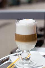 Layers of latte coffe in glass cup on table of cafe