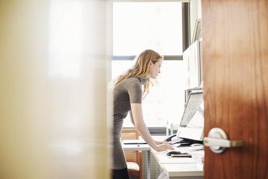 A woman in an office, seen through an open door. 