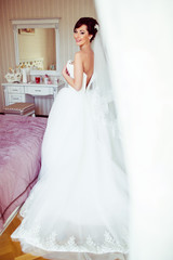 The beautiful bride stands near bed