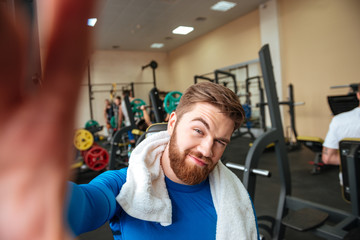 Fototapeta na wymiar Young sportsman sitting in gym and make selfie.