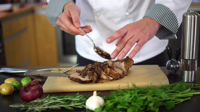 chef putting sauce, spices and herbs on roasted meat