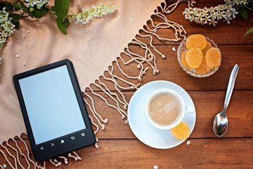 Obraz na płótnie Canvas The e-book reader and coffee on a wooden table
