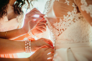 The bridesmaids helping to wear a wedding dress for bride