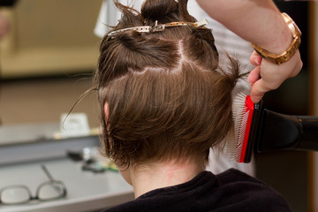 hairdresser drying female client's wet hair