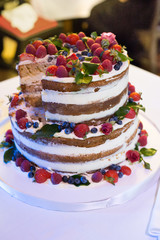 Obraz na płótnie Canvas wedding rustic cake with fresh fruits green leaves and living natural flowers