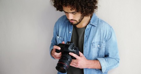 Photographer looking at photos on digital camera in studio 4k