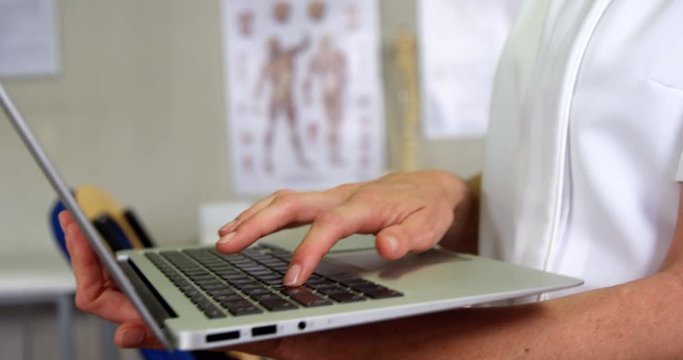 Female physiotherapist using laptop in clinic 4k