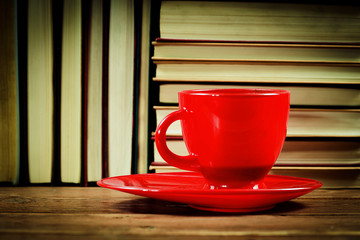 A cup of coffee on a background heap of books