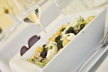 Tilted view of a Mediterranean salad with cheese, crisps and olives