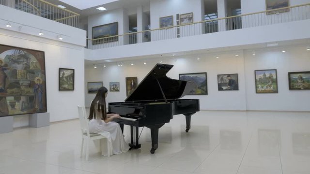 Musical pianist playing classical grand piano in a center of concert hall. 4K.