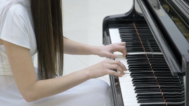 Woman musician hands playing a grand piano. 4K.