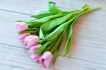 gentle spring bouquet of pink tulips on a light wooden background
