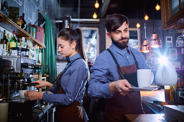 Bartender waiter with a kettle and mug of coffee tea working in the workplace bar, cafe.