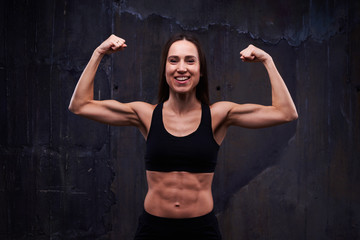 Fototapeta premium Happy fitness model showing trained biceps isolated against blac
