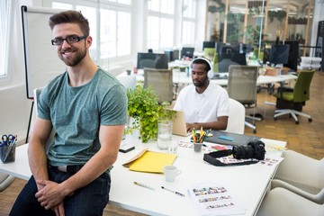 Portrait of smiling graphic designer sitting on his desk