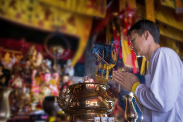 Man praying for new year ,lighting incense to Buddha.
Burning joss stick at chinese shrine for making merit in chinese new year festival. 
May his life be blessed with health  and happiness .