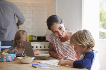Obraz na płótnie Canvas Kids doing homework at kitchen table with mum, close up