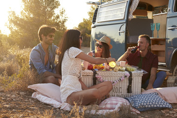 Friends on a road trip  having a picnic beside a camper van