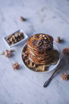 Stack of pancakes topped with maple syrup, walnuts and cacao nib