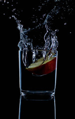 fresh red apple with droplets of water against black background reflection