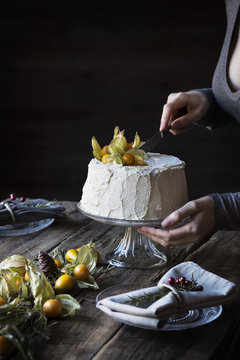 Woman cutting a chiffon cake on wooden table